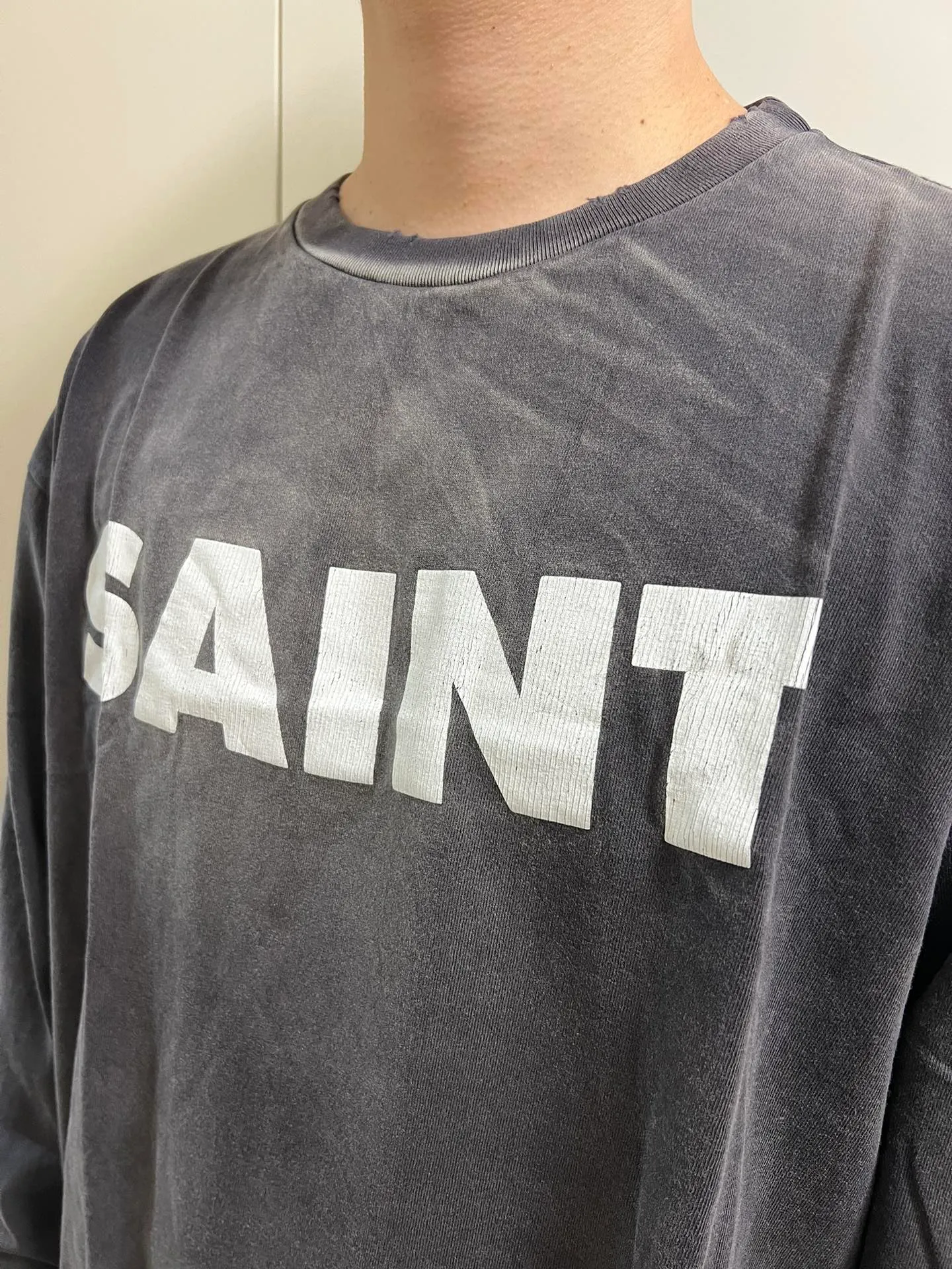 SAINT Mxxxxxx S>N>T LS TEE/BLACK Autumn and winter new style S>N>T slogan crack printed long TEE, washed black S-XL Asut ready-made garments dyed, the whole piece sprayed with horse-hair spray, and then sprayed again to fade the color. The collar and cuffs are frayed. Many hangings are worn NEW VINTAGE. Heavy craftsmanship.